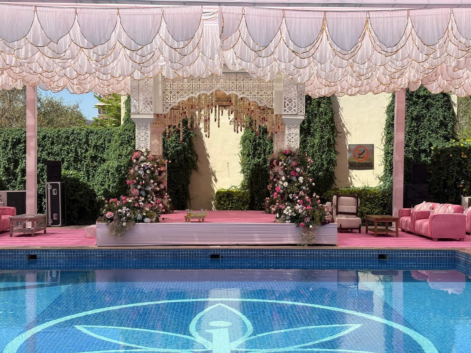 Poolside mandap with a draped canopy and floral pillars