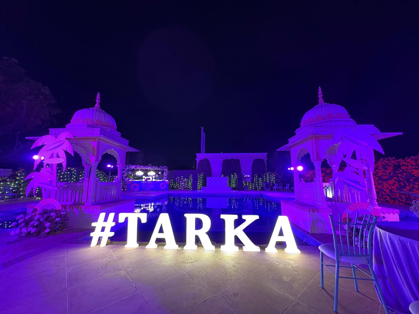 Poolside evening reception with illuminated signage and uplighting