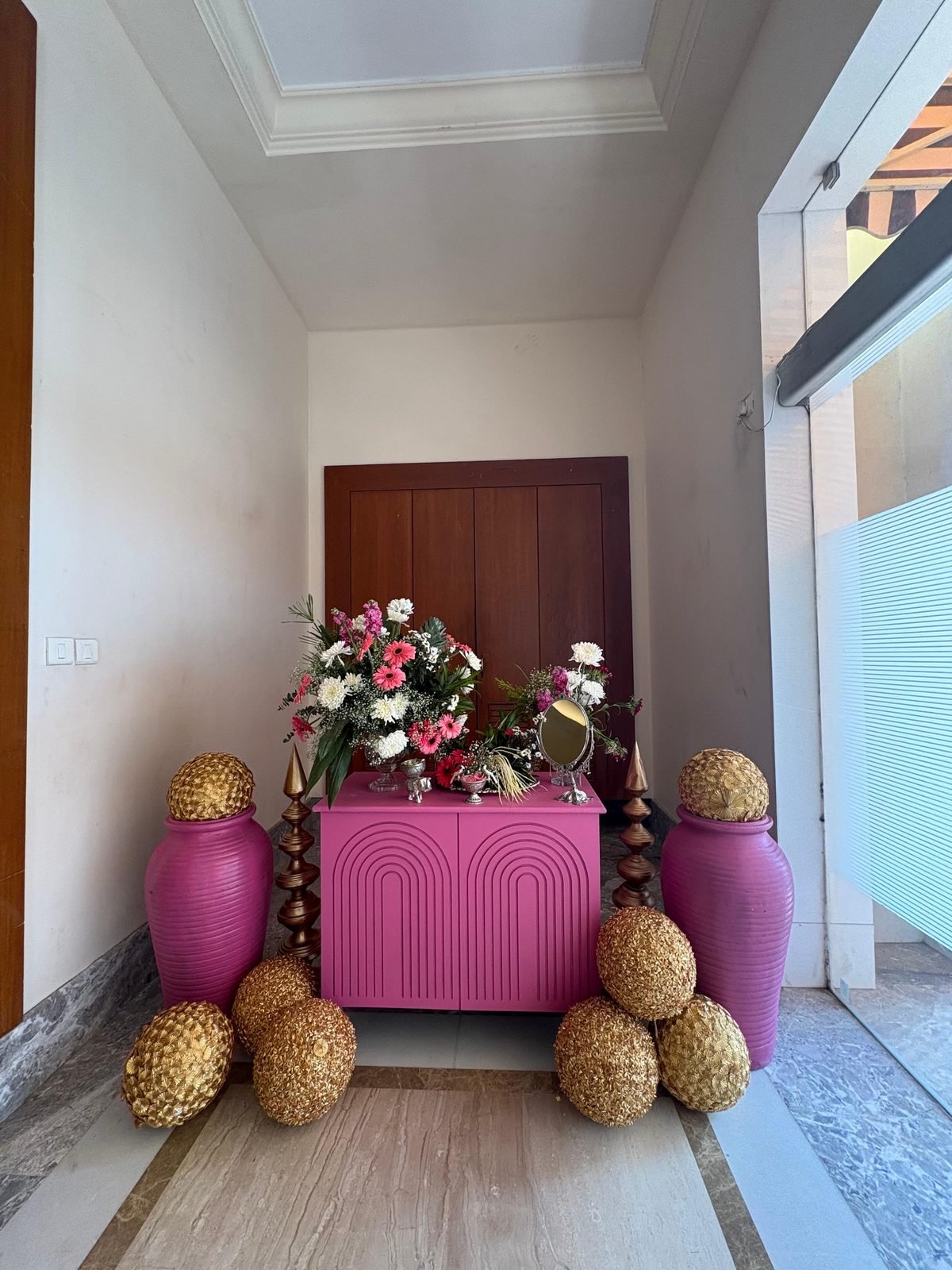 Floral welcome display with gold urns at a wedding entrance